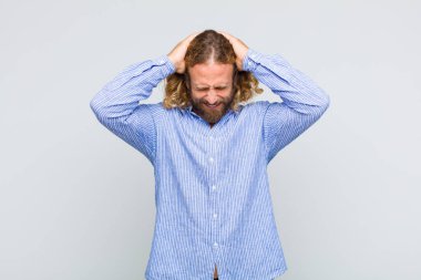 Sarışın bir adam stresli ve hayal kırıklığına uğramış hissediyor. Eli kolu bağlı, yorgun, mutsuz ve migren ağrısı çekiyor.