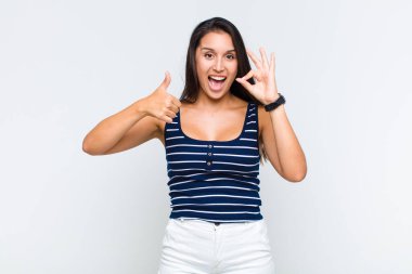 Genç bir kadın mutlu, şaşkın, tatmin olmuş ve şaşırmış hissediyor, iyi görünüyor ve el kol hareketleri yapıyor, gülümsüyor.