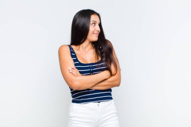 Genç bir kadın omuz silkiyor, kafası karışık ve kararsız, kolları bağlı ve şaşkın görünüyor.