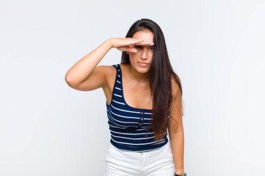 Genç kadın şaşkınlık ve şaşkınlık içinde bakıyor, el üstünde uzak bakıyor, izliyor ya da arıyor.