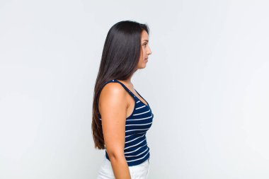 Profil görünümlü genç kadın ilerideki boşluğu kopyalamaya çalışıyor, düşünüyor, hayal ediyor ya da hayal kuruyor.