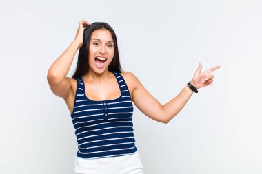 Genç bir kadın gülüyor, mutlu, pozitif ve şaşırmış görünüyor. Yan fotokopi alanını işaret eden harika bir fikrin farkına varıyor.