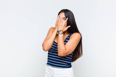 Genç bir kadın korkmuş ya da utanmış hisseder. Gözleri yarı kapalı bir şekilde dikizler ya da gözetler.