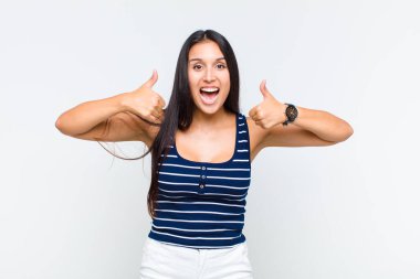 Genç bir kadın gülümseyerek mutlu, pozitif, kendinden emin ve başarılı görünüyor.