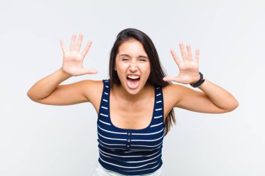 Genç bir kadın panik ya da öfke içinde bağırıyor. Şok olmuş, korkmuş ya da öfkeli. Elleri başının yanında.