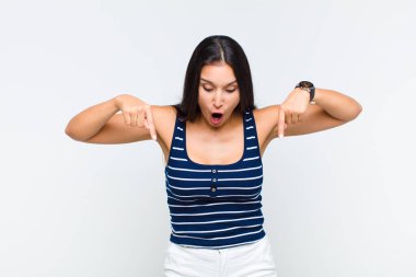 Genç bir kadın şok olmuş, ağzı açık ve şaşkın, inançsızlık ve şaşkınlık içinde bakıyor ve onu işaret ediyor.