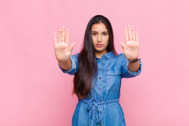 Ciddi, mutsuz, kızgın ve hoşnutsuz görünen genç bir kadın ya da her iki avucunun içinde de dur diyen bir kadın.
