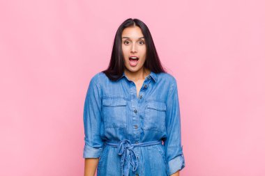 Şok olmuş ya da şaşırmış genç bir kadın ağzı açık bir şekilde 