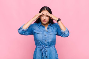 Stresli ve hayal kırıklığına uğramış görünen genç bir kadın, baskı altında baş ağrısı ve sorunlarla çalışıyor.