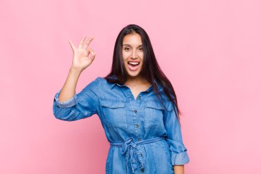 Genç bir kadın kendini başarılı ve tatmin olmuş hissediyor, ağzı açık gülümsüyor, elle işaret veriyor.