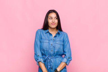 Genç kadın merak ediyor, mutlu düşünceler ve fikirler düşünüyor, hayal kuruyor, kenarda yer arıyor.