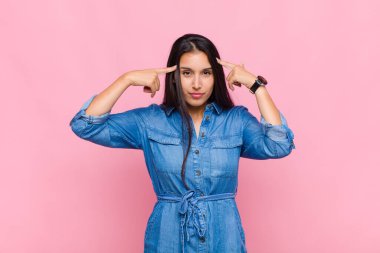 Ciddi ve konsantre görünümlü genç bir kadın, beyin fırtınası yapıyor ve zorlu bir sorunu düşünüyor.