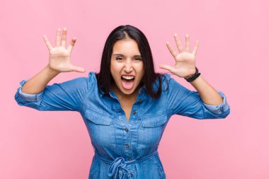 Genç bir kadın panik ya da öfke içinde bağırıyor. Şok olmuş, korkmuş ya da öfkeli. Elleri başının yanında.