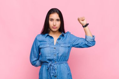 Genç kadın kendini ciddi, güçlü ve asi hissediyor, yumruğunu kaldırıyor, protesto ediyor ya da devrim için savaşıyor.