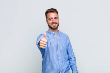 Genç adam gururlu, kaygısız, kendinden emin ve mutlu, olumlu gülümsüyor.