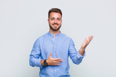 Genç adam gururla ve güvenle gülümsüyor, mutlu ve tatmin olmuş hissediyor ve fotokopi alanında bir konsept gösteriyor.