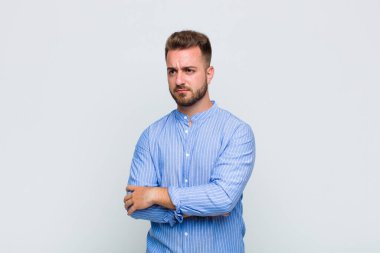 Genç adam üzgün, üzgün ya da kızgın ve olumsuz bir tavırla, anlaşmazlık içinde somurtuyor.