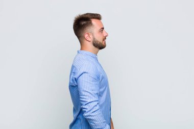 Profil görünümlü genç adam ilerideki boşluğu kopyalamaya çalışıyor, düşünüyor, hayal ediyor ya da hayal kuruyor.