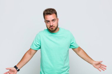 young man feeling clueless and confused, having no idea, absolutely puzzled with a dumb or foolish look