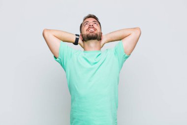 Genç adam gülümsüyor ve rahatlıyor, tatmin oluyor, kaygısız, neşeli ve rahatlatıcı.