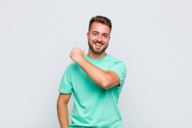 Genç adam mutlu, pozitif ve başarılı hissediyor, bir meydan okumayla karşılaştığında motive oluyor veya iyi sonuçları kutluyor.