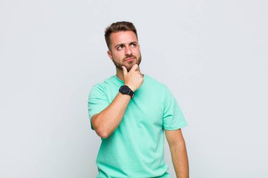 Genç adam düşünüyor, kuşkulu ve şaşkın hissediyor, farklı seçeneklerle, hangi kararı vereceğini merak ediyor.