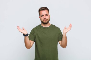 Genç adam şaşkın ve şaşkın hissediyor, şüpheci, farklı seçenekleri tartıyor veya komik bir ifadeyle seçiyor.