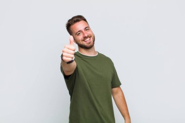 Genç adam gururlu, kaygısız, kendinden emin ve mutlu, olumlu gülümsüyor.