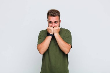 Genç adam endişeli, gergin, stresli ve korkmuş görünüyor. Tırnaklarını yiyor ve yanal fotokopi alanı arıyor.