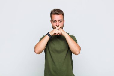 Genç adam ciddi ve hoşnutsuz görünüyor. İki parmağının önde olması reddedilerek sessizlik istiyor.