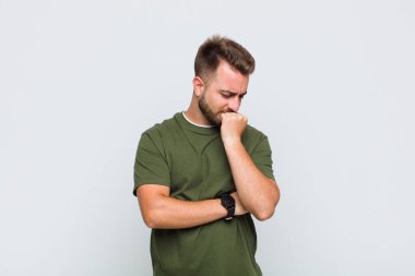 Genç adam ciddi, düşünceli ve endişeli, elleri çenesine bastırılmış, yan bakıyor