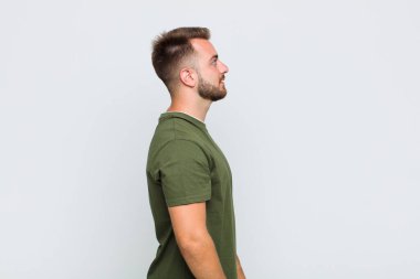 Profil görünümlü genç adam ilerideki boşluğu kopyalamaya çalışıyor, düşünüyor, hayal ediyor ya da hayal kuruyor.