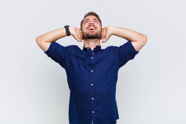 Genç adam gülümsüyor ve rahatlıyor, tatmin oluyor, kaygısız, neşeli ve rahatlatıcı.