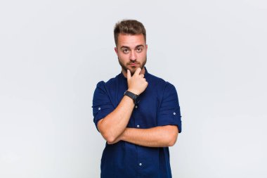 Genç adam ciddi görünüyor, kafası karışık, kararsız ve düşünceli, seçenekler ve seçimler arasında şüpheci.