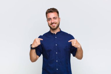 Genç adam gururlu, pozitif ve iki eliyle göğsünü gösteren