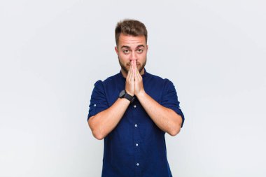 Genç adam endişeli, üzgün ve korkmuş hissediyor, elleriyle ağzını kapatıyor, endişeli ve berbat görünüyor.