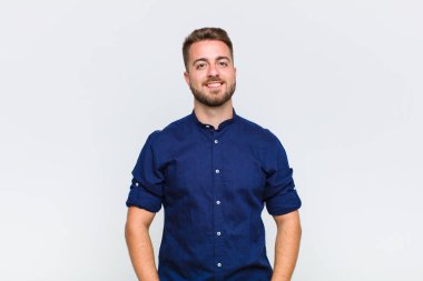 Genç adam neşeli bir şekilde gülümsüyor. Olumlu, mutlu, kendinden emin ve rahat bir ifadeyle.