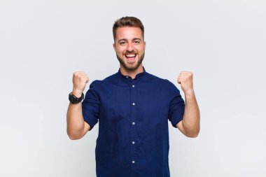 Genç adam öfkeli bir ifadeyle ya da yumruklarıyla başarıyı kutlarken agresif bir şekilde bağırıyor.