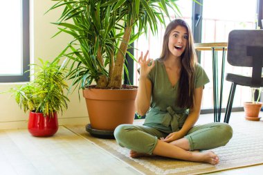 Güzel bir kadın kendini başarılı ve tatmin olmuş hissediyor, ağzı açık gülümsüyor, elle işaret veriyor.