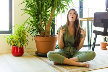 Güzel bir kadın şaşkınlık ve şaşkınlık dolu bir bakışla yukarıyı işaret ederek huşu içinde ve ağzı açık hisseder.