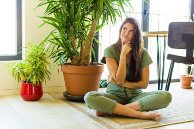 Güzel bir kadın düşünüyor, kuşkulu ve şaşkın hissediyor, farklı seçeneklerle, hangi kararı vereceğini merak ediyor.