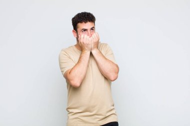 Genç adam endişeli, gergin, stresli ve korkmuş görünüyor. Tırnaklarını yiyor ve yanal fotokopi alanı arıyor.