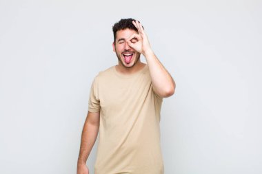 Genç adam mutlu bir şekilde gülümsüyor, şaka yapıyor ve gözetleme deliğinden bakıyor, sırları gözetliyor.