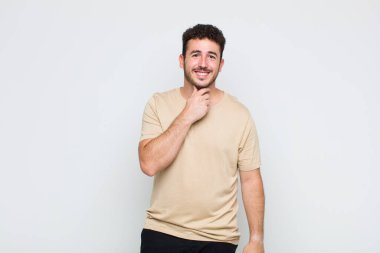 Genç adam gülümsüyor, hayattan zevk alıyor, mutlu, arkadaş canlısı, tatmin olmuş ve tasasız.