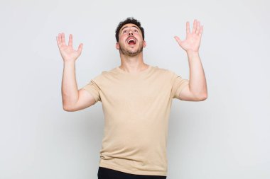 Genç adam mutlu, şaşkın, şanslı ve şaşırmış hissediyor, zaferi kutluyor, iki eli havada.