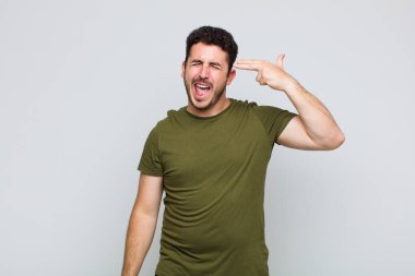 Genç adam mutsuz ve stresli görünüyor, intihar jesti elle silah işareti yapıyor, kafasını işaret ediyor.