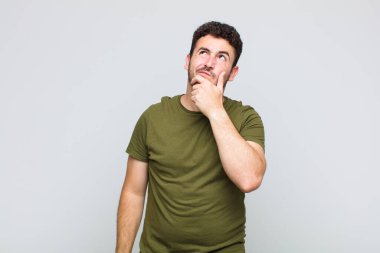 Genç adam düşünüyor, kuşkulu ve şaşkın hissediyor, farklı seçeneklerle, hangi kararı vereceğini merak ediyor.