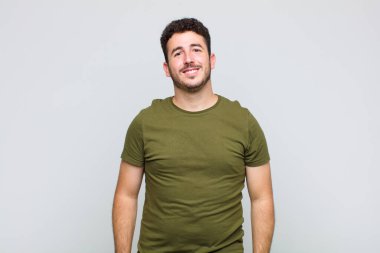 Genç adam neşeli bir şekilde gülümsüyor. Olumlu, mutlu, kendinden emin ve rahat bir ifadeyle.