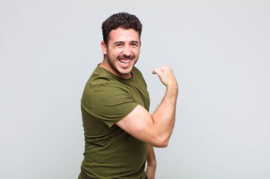 Genç adam kendini mutlu, tatmin olmuş ve güçlü hissediyor, kaslı ve formda, spor salonundan sonra güçlü görünüyor.