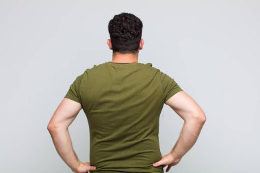 Genç adam kafası karışık ya da dolu hissediyor ya da şüphe ve sorular, merak ediyor, elleri kalçasında, dikiz aynasından